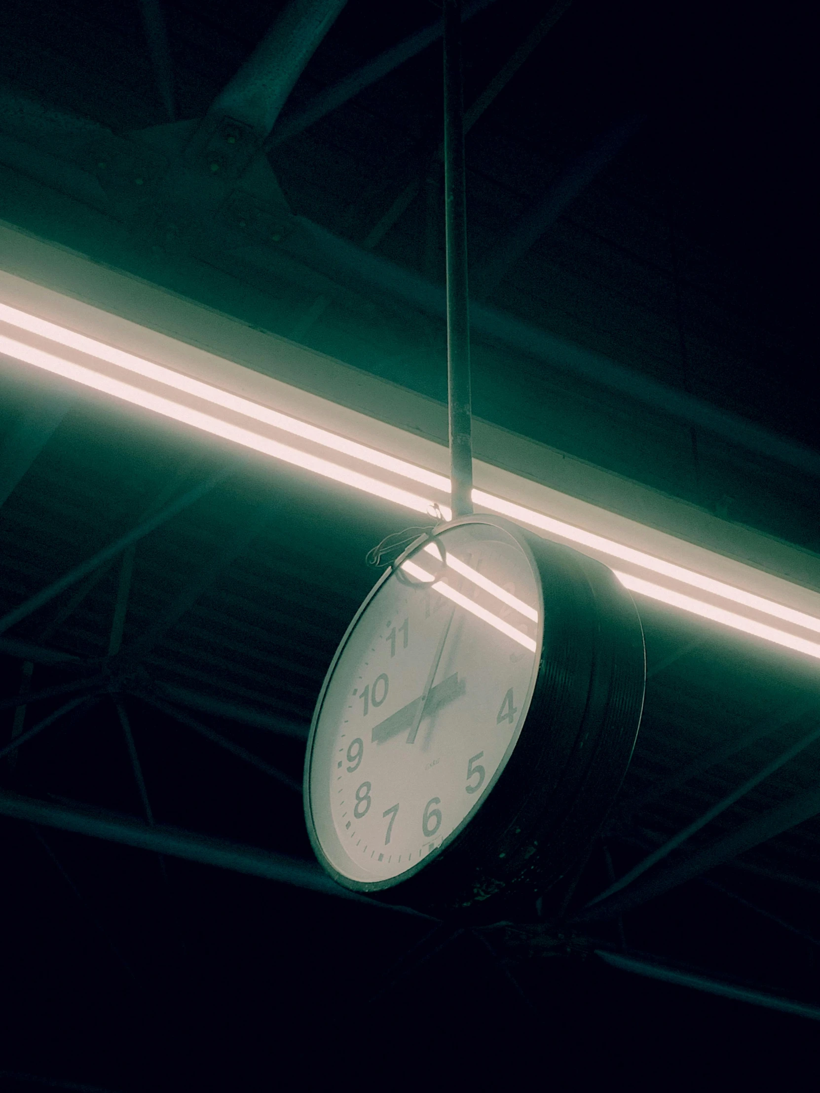 a clock hangs below some neon lights