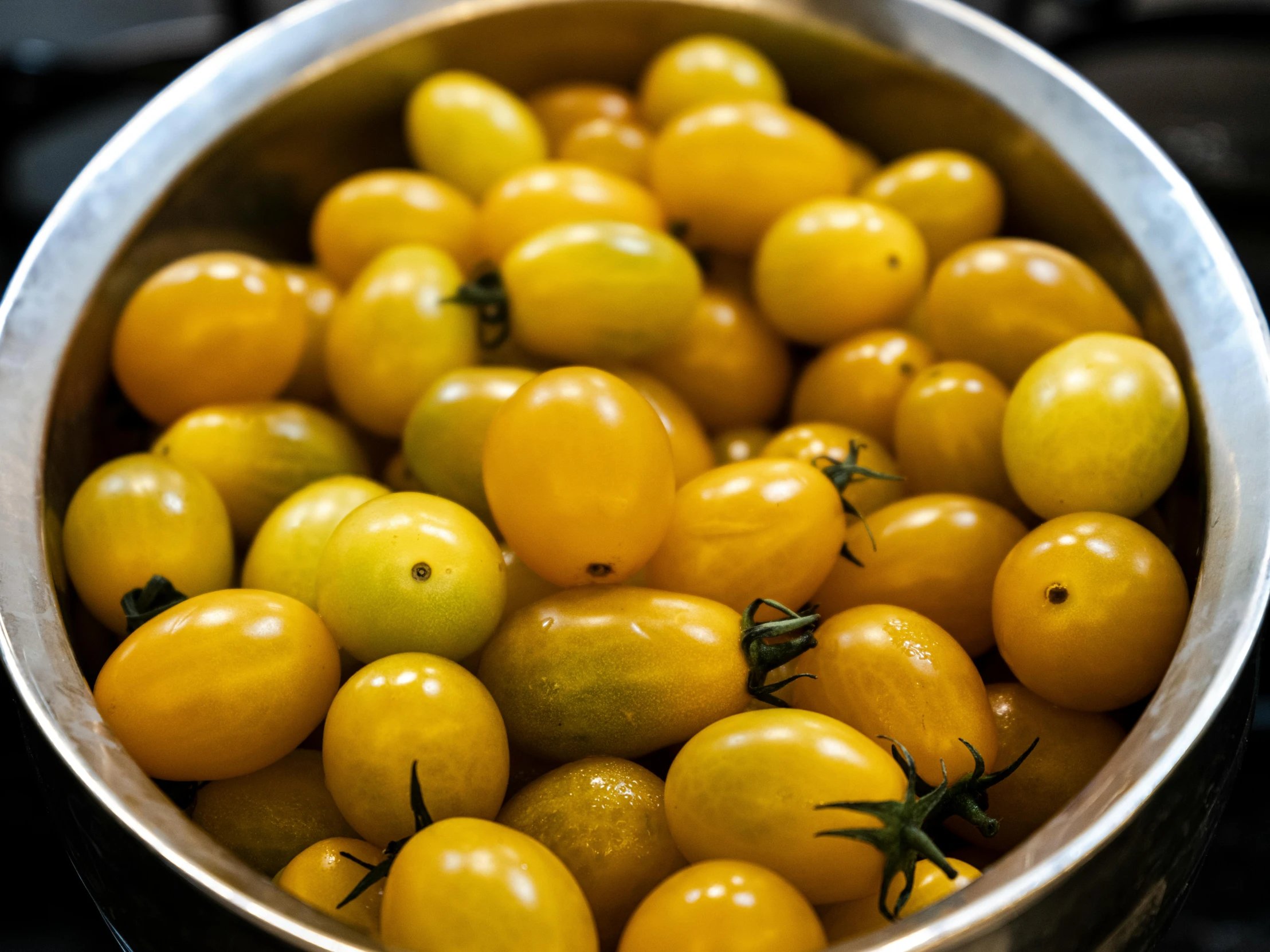 a large metal bowl with small yellow tomatoes