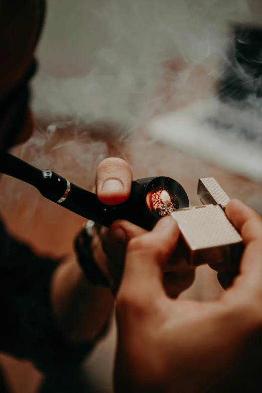 a close up of a person holding a cigarette with smoke