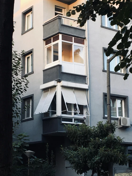 the building is gray with white balconies and windows