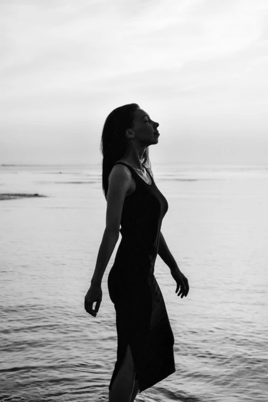 a woman is walking along the beach on a cloudy day