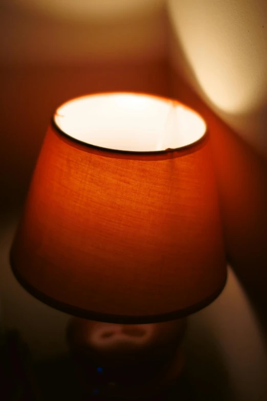 the small lamp shade is orange against the wall