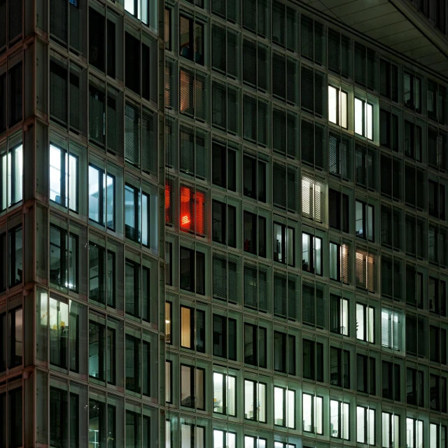 several windows on a tall building with a clock at night