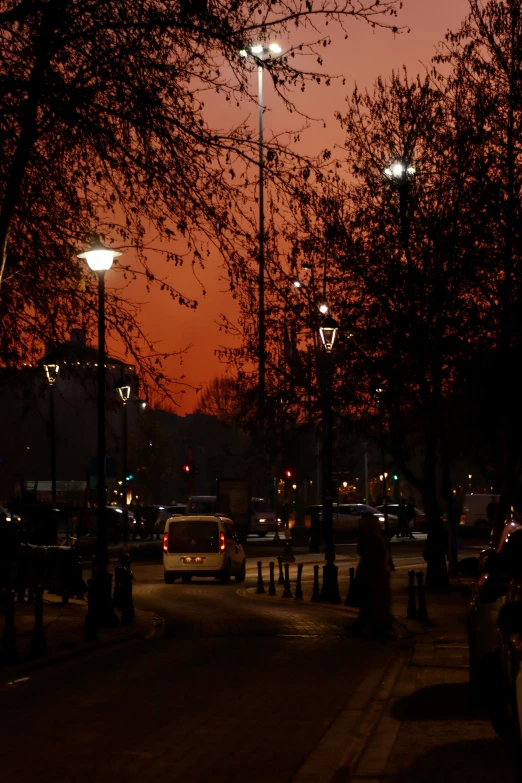 people walking on the street at night next to some lights