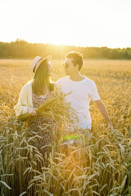 two people standing in a wheat field, one holding a plant