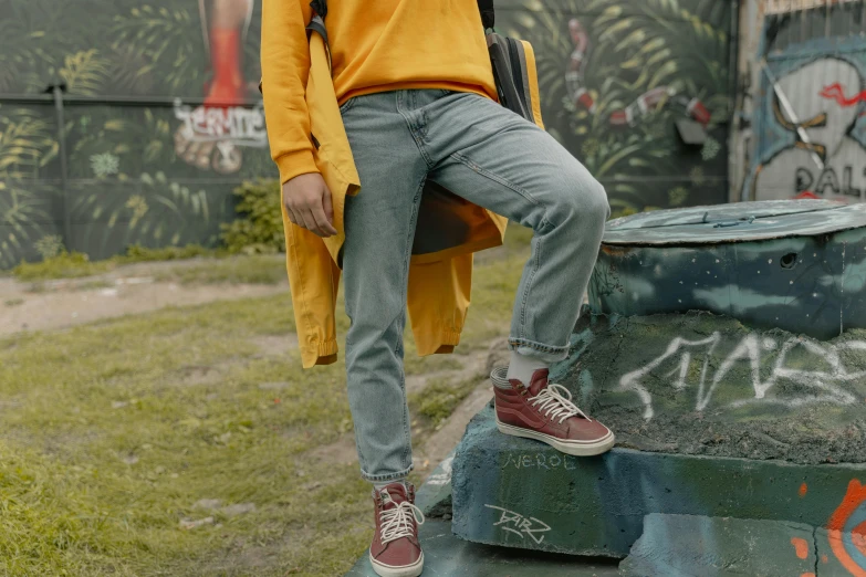 a young man in yellow shirt and jeans sitting on a bench