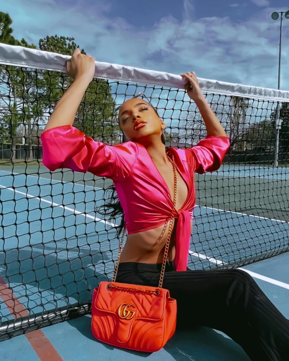 a woman is sitting on the tennis court, holding onto the net