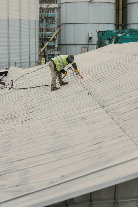 the worker on the roof is using a pair of scissors