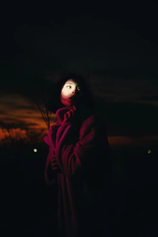 a person in red hooded coat with dark background