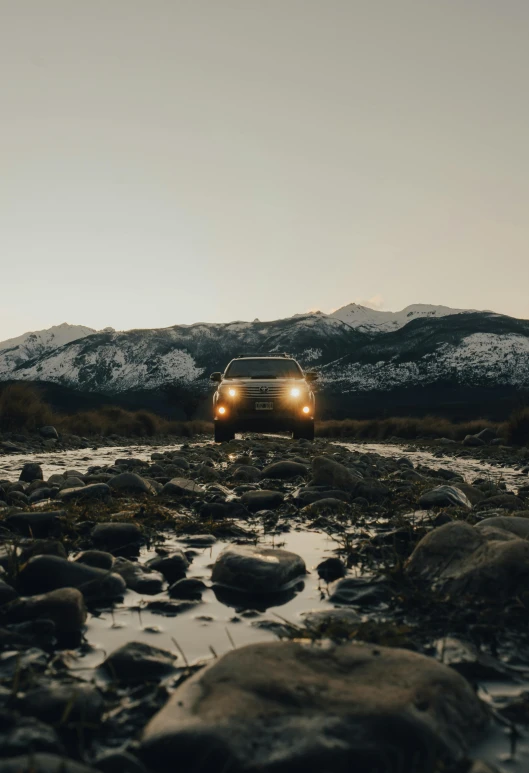 a vehicle driving on rocks along the river bank