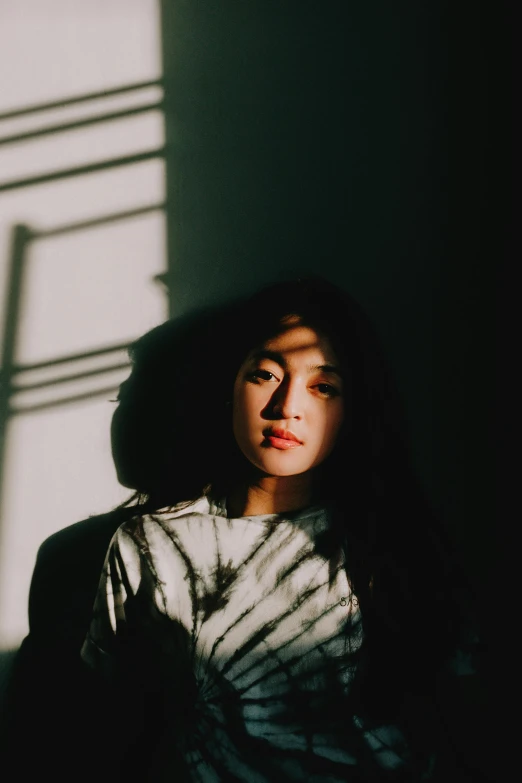 a young woman with long dark hair standing in the shadows