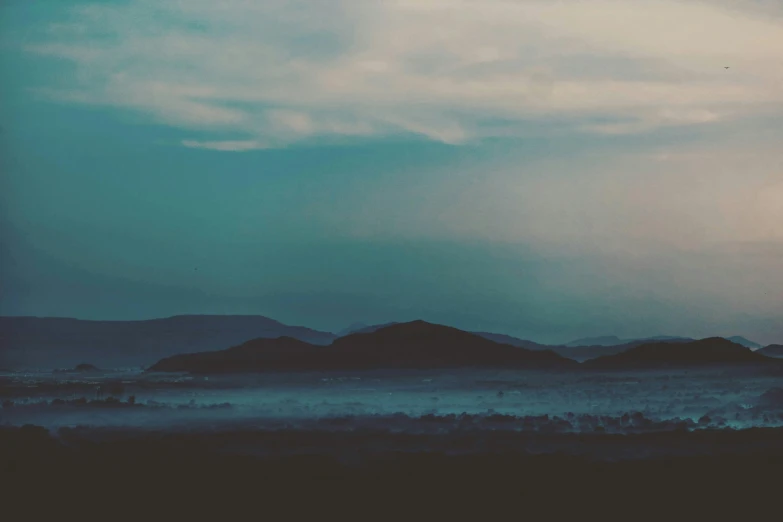 a blue and gray cloudy sky is above some hills