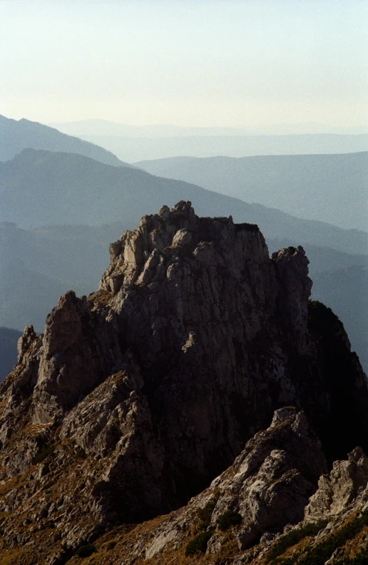 a lone person stands on top of a large rock
