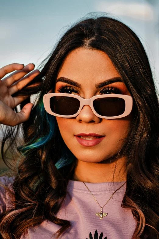 woman with dark hair wearing sunglasses, standing outdoors