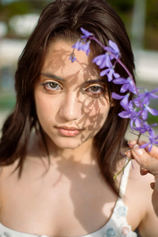 a young woman holding purple flowers near her face