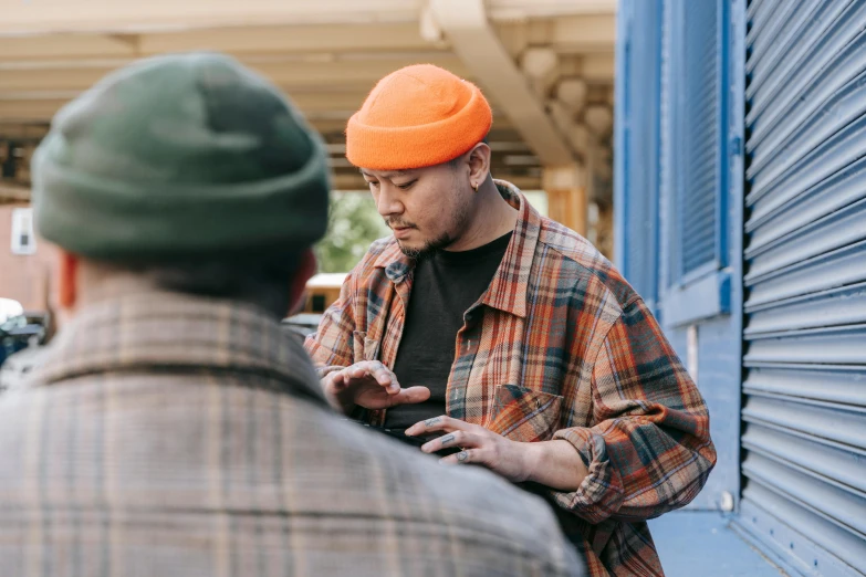 a man is wearing an orange hat and standing next to a wall