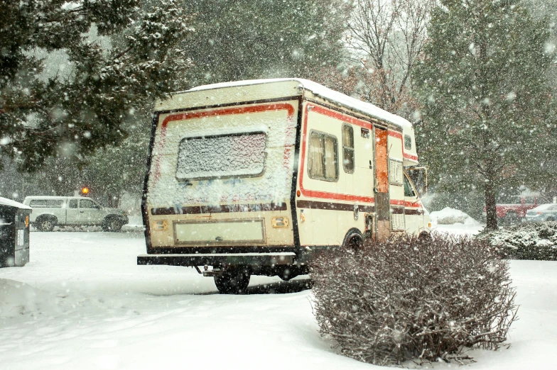 a small white trailer is parked in the snow