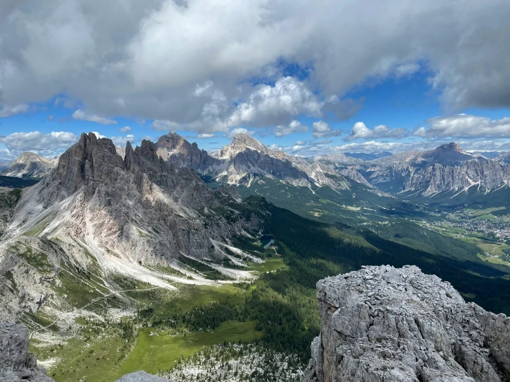 a valley below the mountains covered in green trees