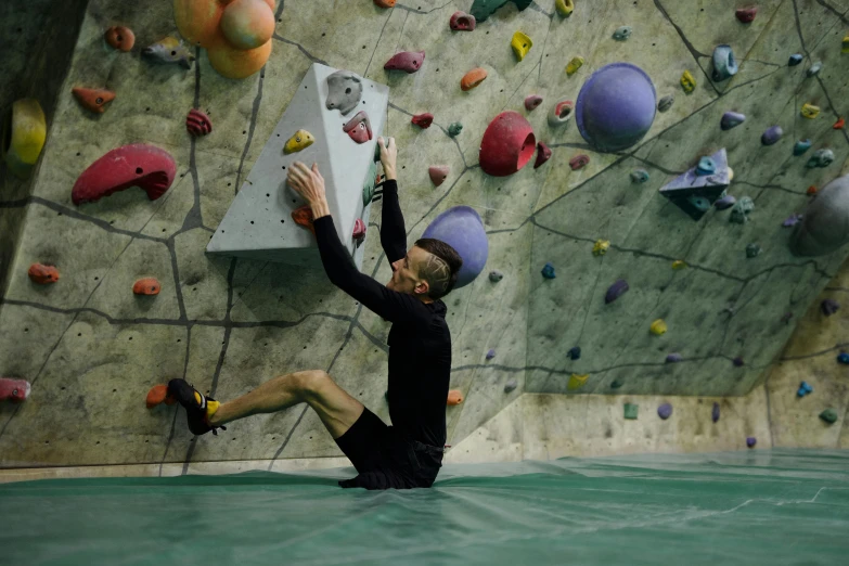 a man climbing up a wall at the bottom of a climbing wall