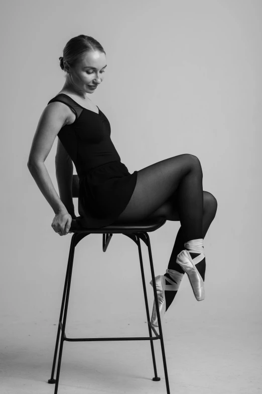 black and white pograph of woman sitting on chair with legs up