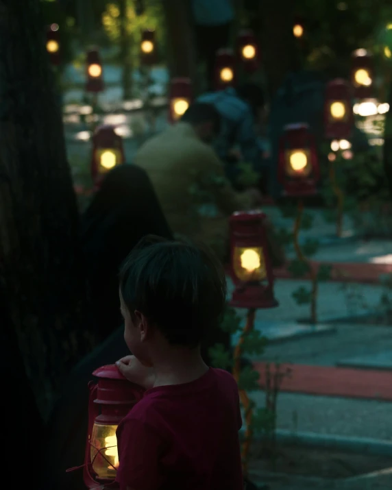 a  in a red shirt looking at lit up lanterns