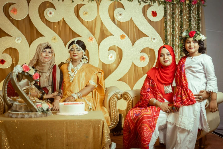 a bride and two daughters in traditional indian outfits pose for the camera