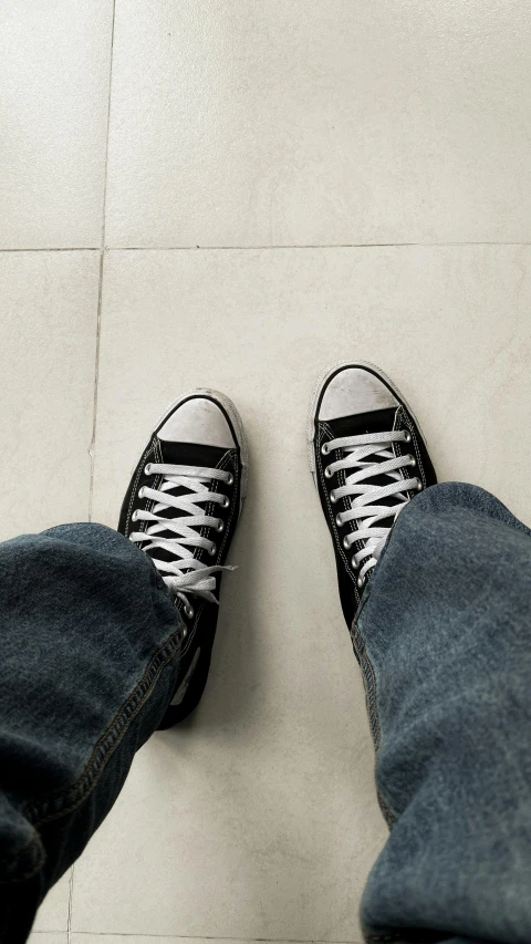 someone's feet on the floor wearing black and white shoes