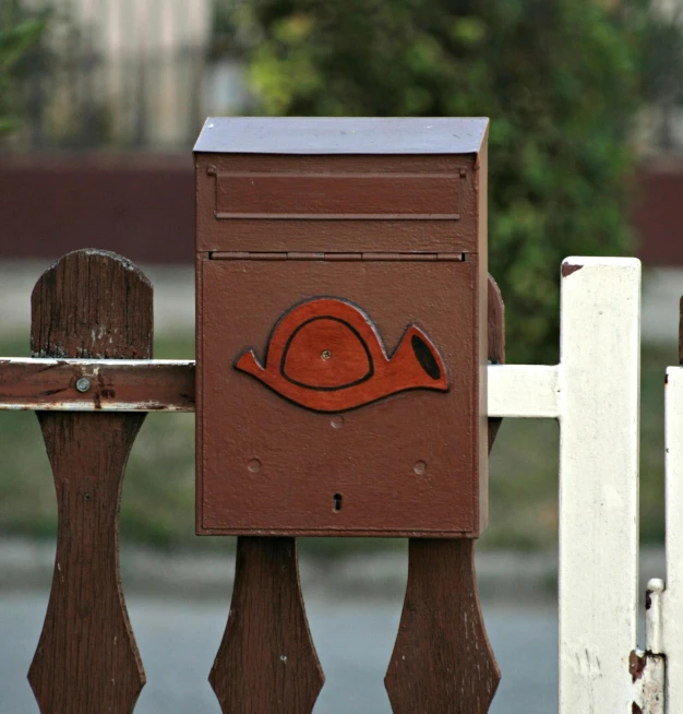a mail box on a wooden fence near a white fence