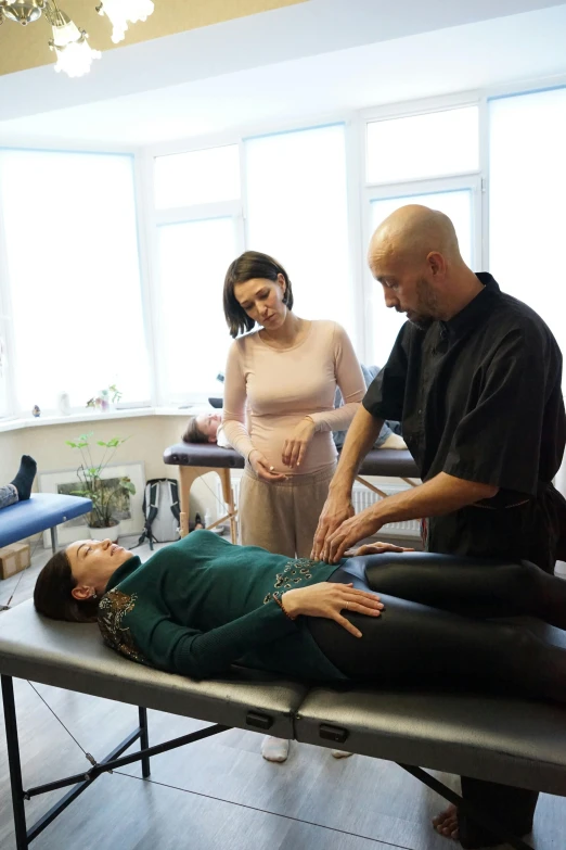 two men looking at a woman laying down on top of a table