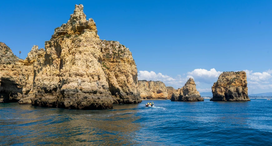 some people are out on the water by some rocks