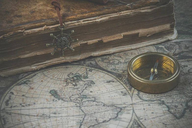 a vintage compass and map with a book