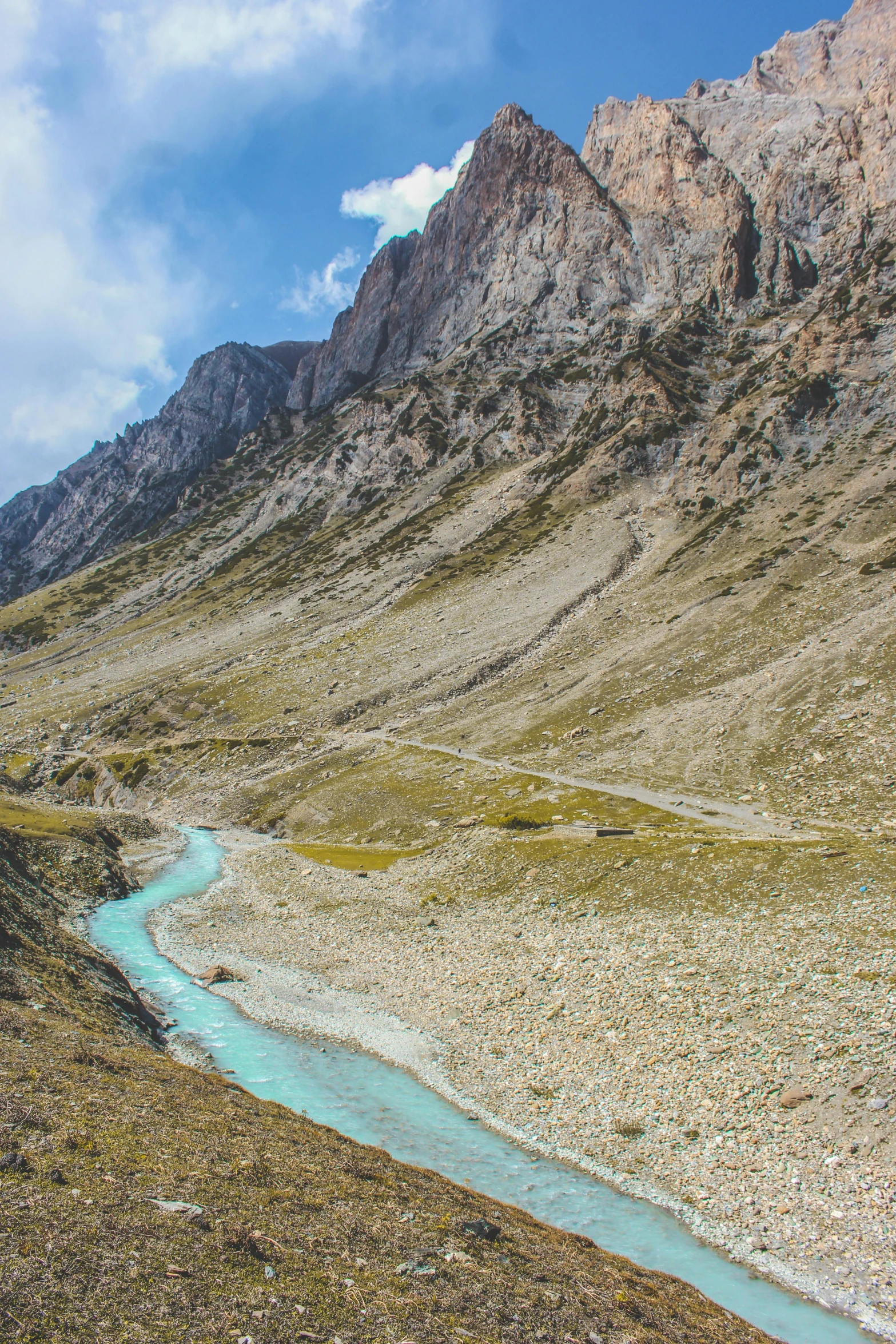 the mountains surrounding a creek meanders down to a riverbed