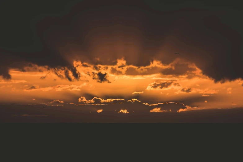 the sun sets behind some dark clouds over the ocean