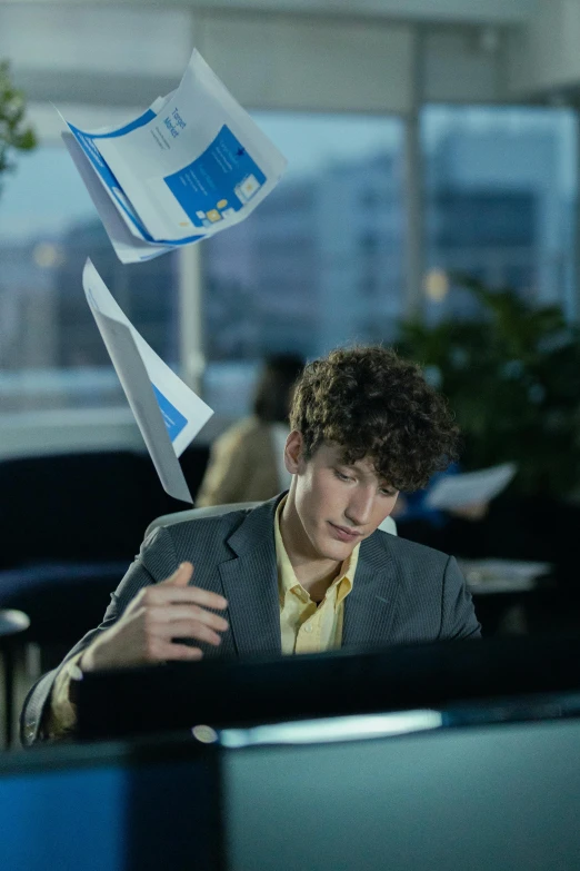 a man in an office looking at his phone while flying a paper airplane