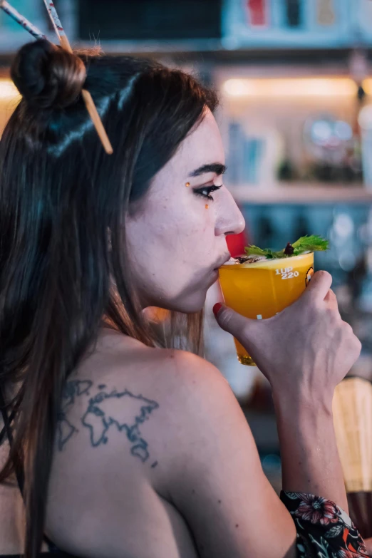 a woman drinking from a yellow drink in a cup