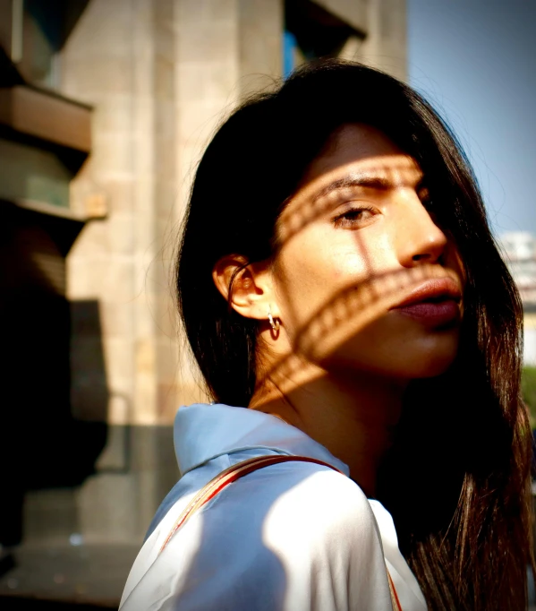 a woman in front of a building with the sun shining on her face