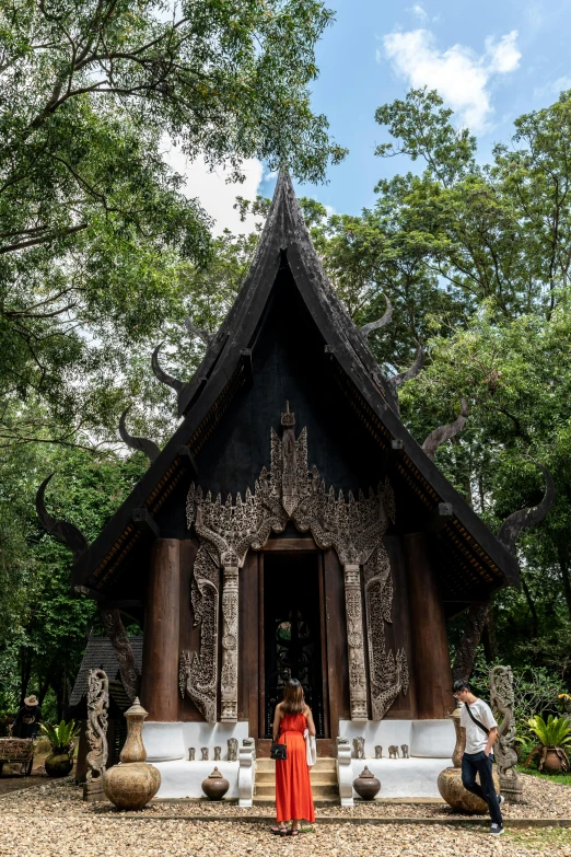 the woman is standing outside of the building with a tall roof