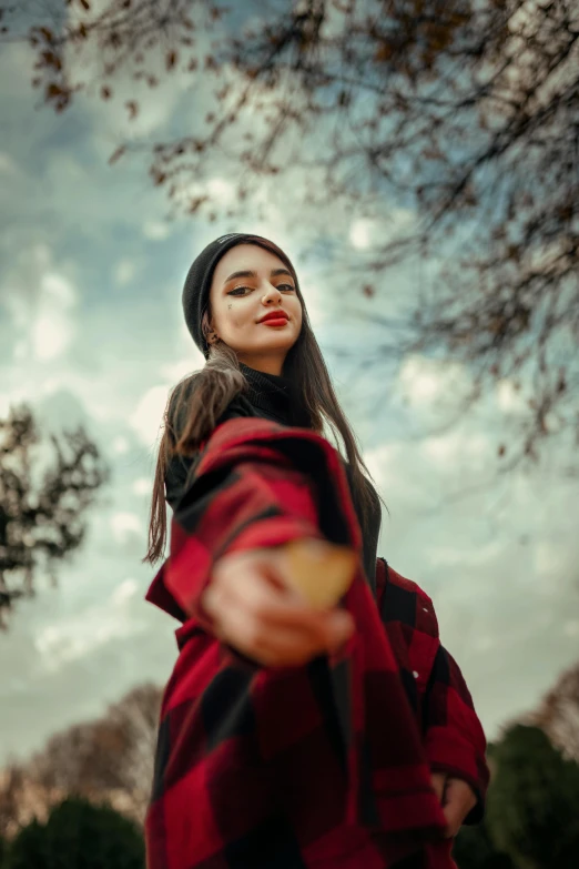 a girl in a red and black jacket looking up at the sky