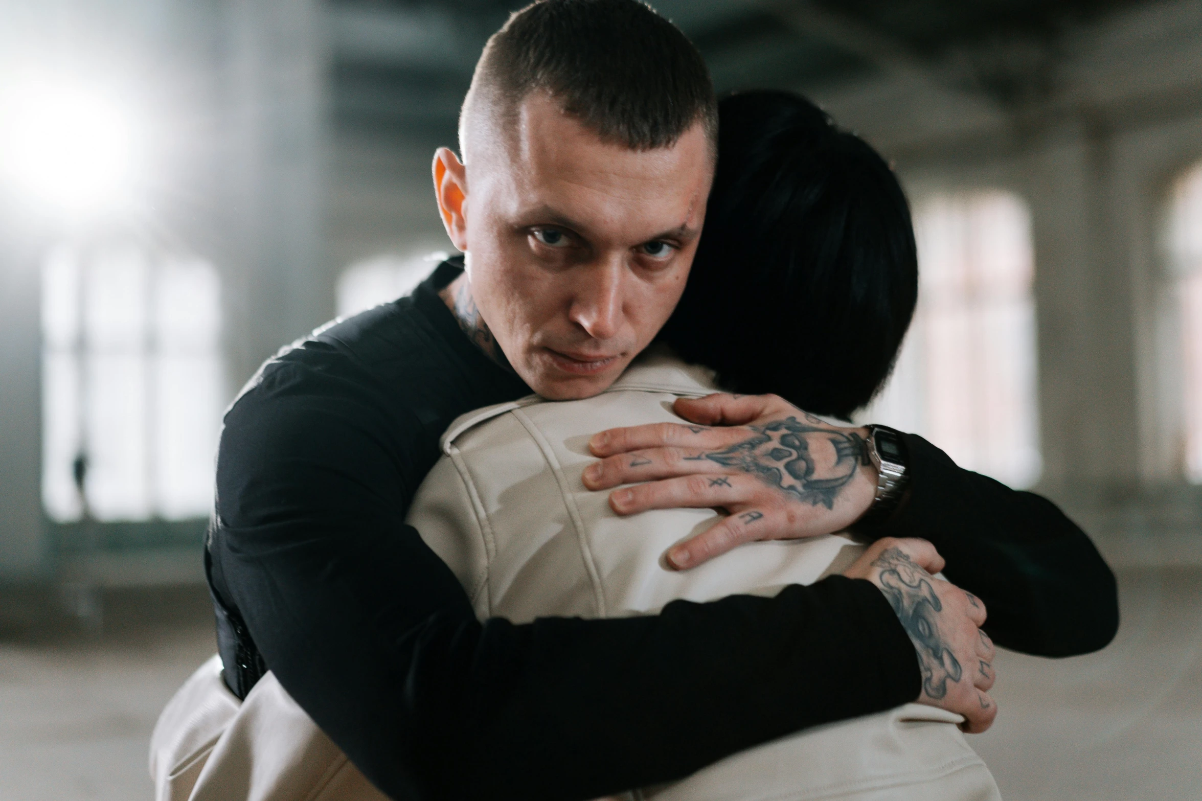 a tattooed man hugging a woman in the middle of a hallway