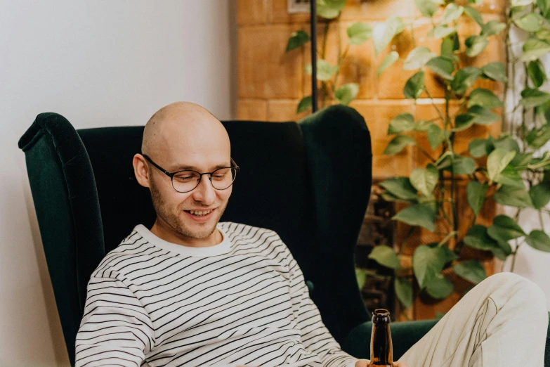 the man is using his phone while he sits in a chair