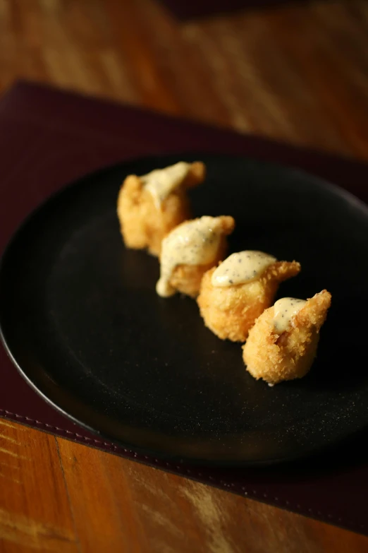 a black plate holding three fried appetizers on top of a table