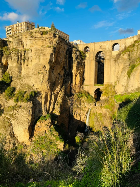 a cliff with an arch and a bridge at the top