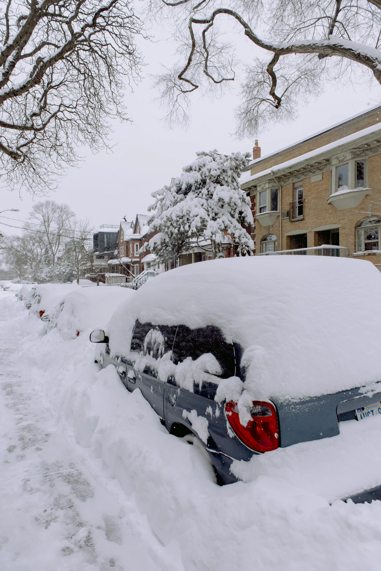 a parked car is covered with snow in a suburban area