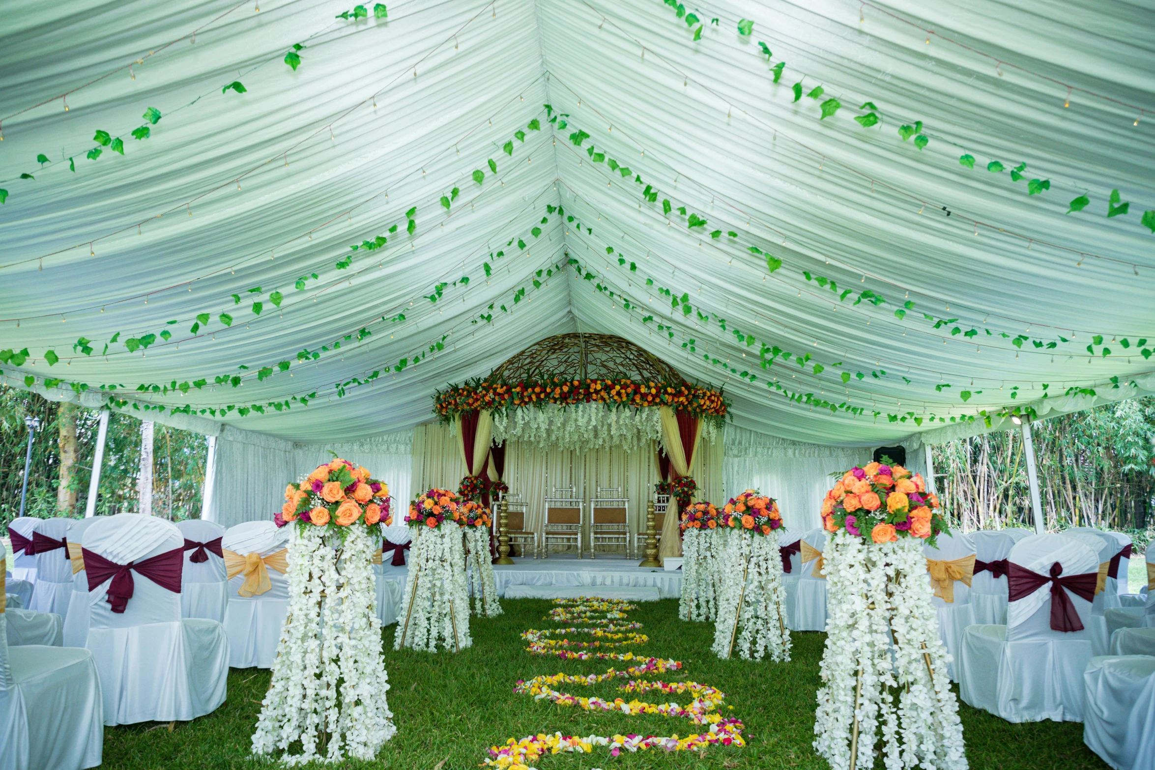 the large tented area has white draping, pink and orange flowers and green leaves