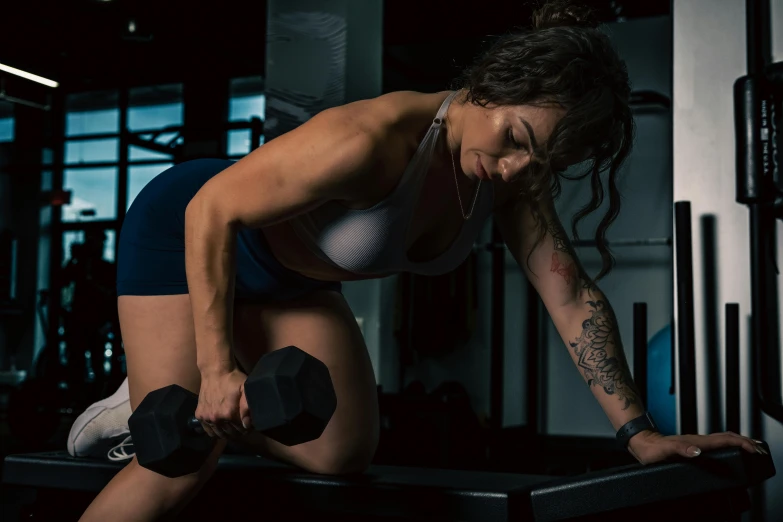 a woman squatting down with her hand behind her head in a gym setting