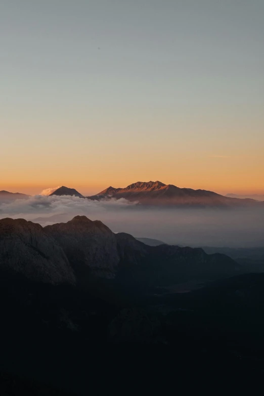 a mountain is seen covered by clouds at sunrise