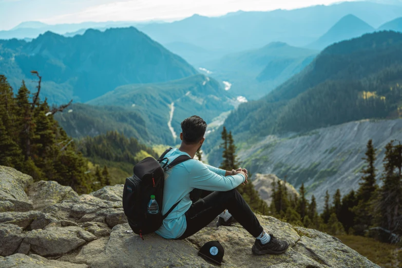 a man sitting on top of a mountain looking at the mountains