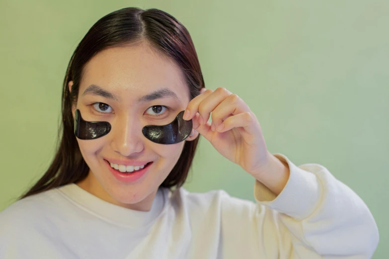 a woman has black makeup and is holding up some rocks