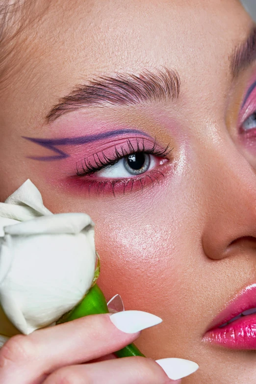 a woman with bright makeup holding a flower in her left hand