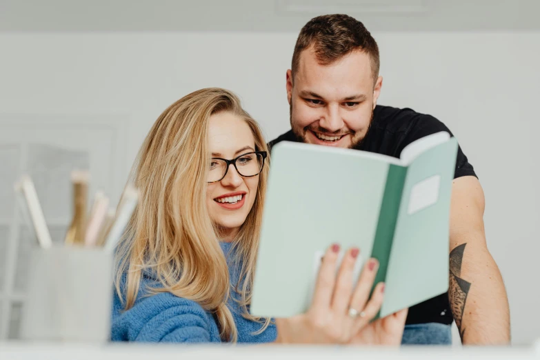 a man is reading a book while a woman is smiling